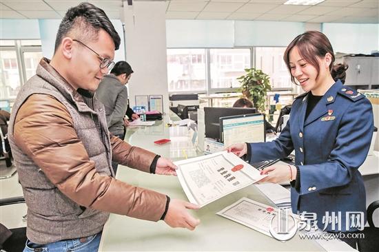 在丰泽区行政服务中心，一家网络科技公司工作人员领取新版营业执照。（陈起拓 摄）